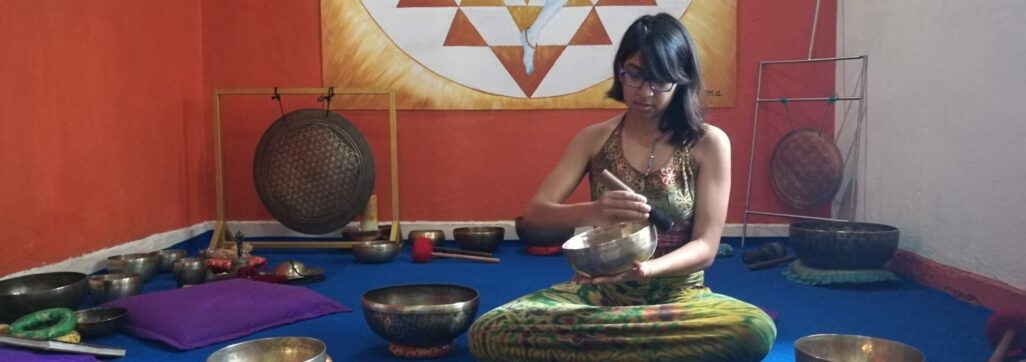 child of the earth playing singing bowls in front of a shiva poster